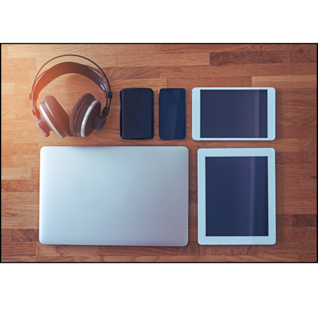 Overhead photo of a desk with a set of headphones, two small zippered bags, a tablet, an iPad, and a silver laptop.